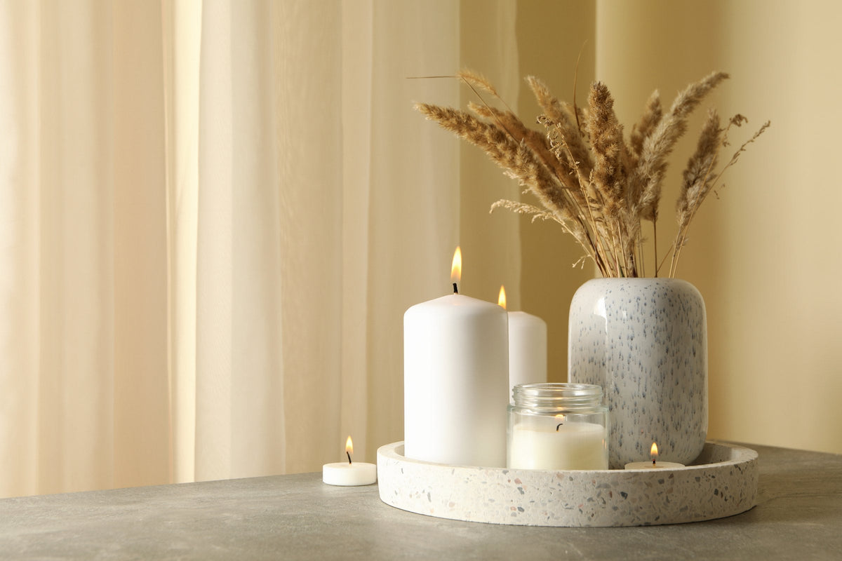 Candles and a reed diffuser on a tray on a grey table
