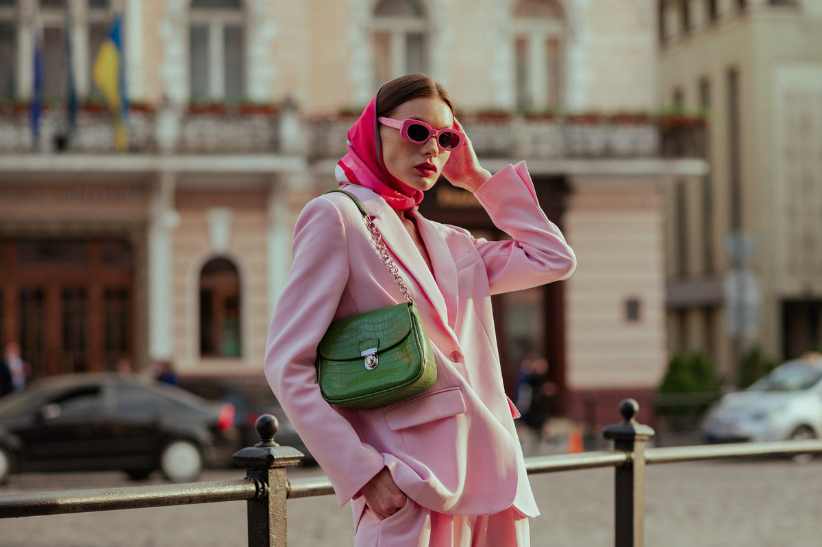 A woman in pink sunglasses, a silk headscarf and a blazer on a European city street