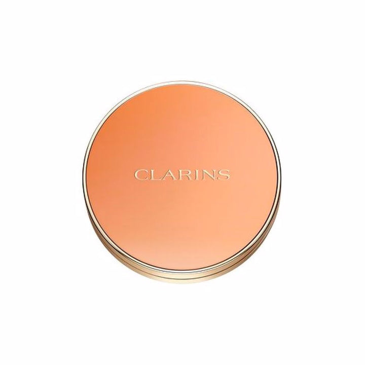 Clarins Round orange compact powder case with metallic rim, embossed brand name, minimalist metal/plastic finish