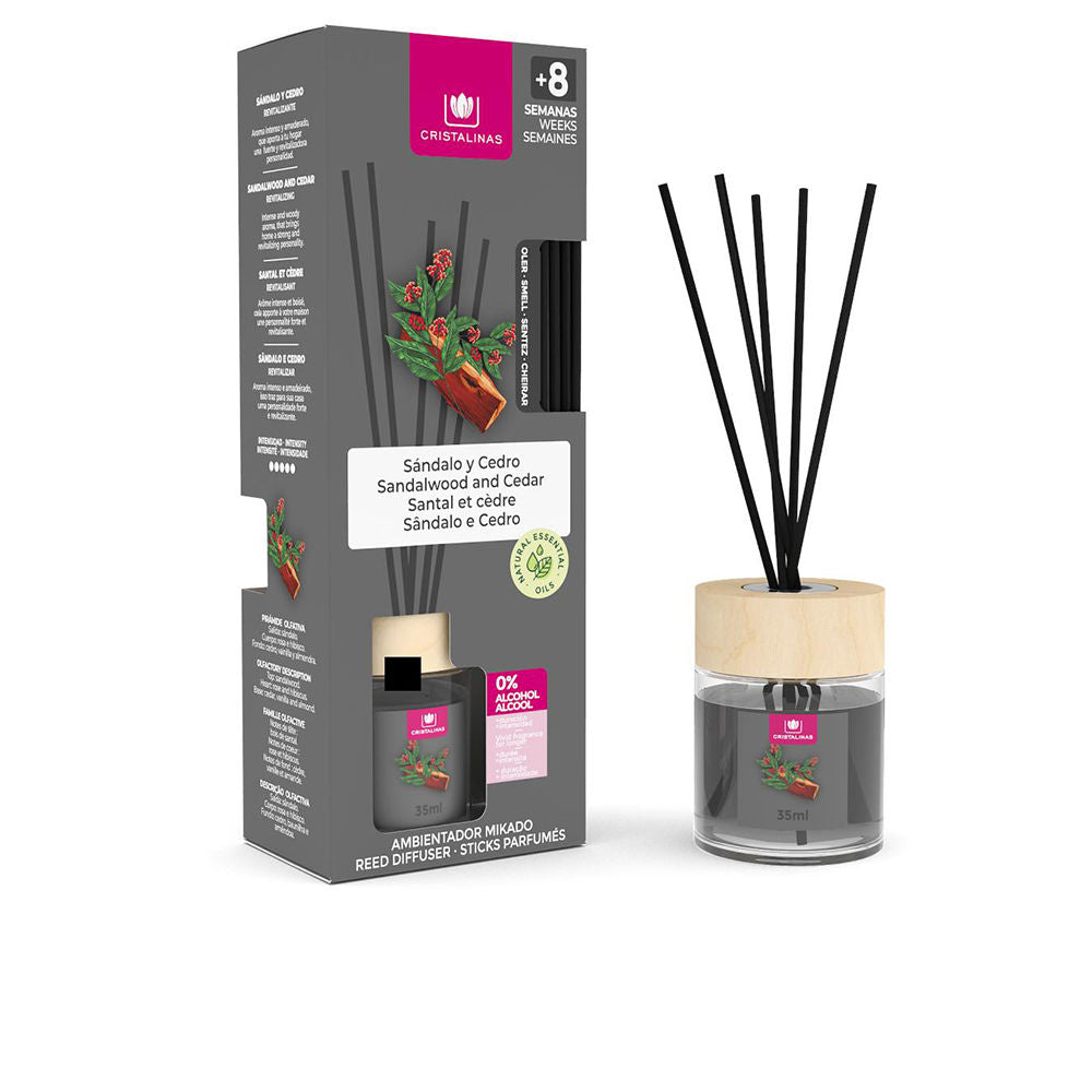 Black glass reed diffuser with wooden cap, clear liquid, floral-wood illustration label — Cristalinas