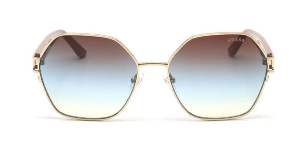 Gold geometric sunglasses with blue-to-brown gradient lenses and decorative gold temple accents on a neutral background