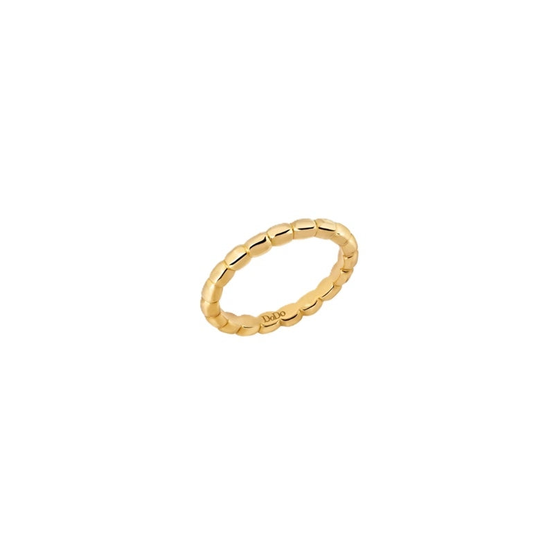 Close-up gold beaded ring on neutral background showing textured band and polished edges